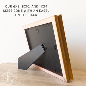 May include: A wooden picture frame with a black backing and a black easel stand. The frame has a light brown finish with a pinkish-beige inner edge. Text on the image reads: "OUR 6X8, 8X10, AND 11X14 SIZES COME WITH AN EASEL ON THE BACK."