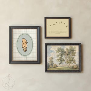 May include: Three framed pictures on a wall. One features Winnie the Pooh, another has a quote, and the third is a landscape painting. The frames are black, and the art has a vintage aesthetic. The Winnie the Pooh art is in an oval shape.