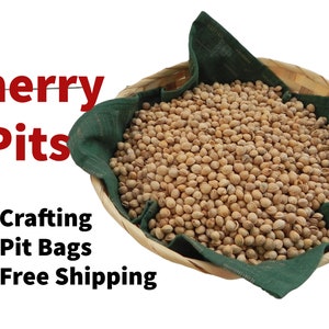 May include: A wicker basket filled with a large quantity of light brown cherry pits. The basket is lined with a dark green cloth. The text "Cherry Pits" is written in red letters above the basket. The text "*Crafting *Pit Bags *Free Shipping" is written in black letters below the basket.