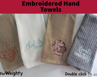 May include: Four embroidered hand towels with different designs. The towels are brown, white, beige, and gray. The designs include a coffee cup, the words "chef-me", a cupcake with the words "Bake Me Away", and the words "Family is Forever".