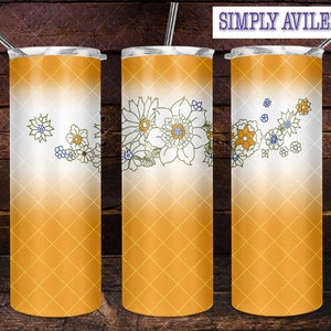 May include: Three stainless steel tumblers with a white and yellow ombre design. The tumblers feature a floral design with a white outline and yellow accents. The tumblers are on a wooden background.