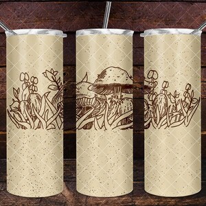 Puede incluir: Tres vasos de acero inoxidable con acabado beige y diseño de setas y follaje marrones. Los vasos están sobre una superficie de madera.