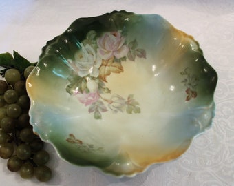 May include: A vintage porcelain bowl with a scalloped edge and a floral design featuring roses and leaves in shades of green, pink, and white.