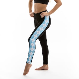 Peut inclure: Leggings noirs avec un motif en losanges bleu et blanc sur le côté. Les leggings sont portés par une personne avec un soutien-gorge de sport noir.