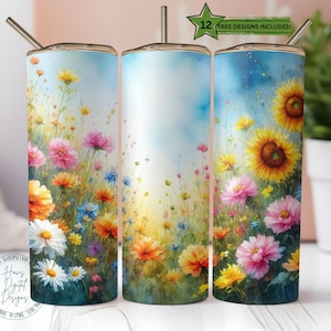 May include: Three stainless steel tumblers with floral designs. The tumblers feature a watercolour painting of colourful wildflowers, including sunflowers, daisies, and other blooms. The background is a gradient of blue and yellow. Each tumbler has a silver straw and a gold lid.