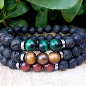 May include: Three stacked bracelets with black lava rock beads, green tiger's eye beads, brown tiger's eye beads, and red tiger's eye beads.