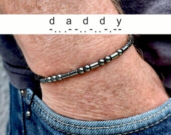 May include: A black beaded bracelet with the word "daddy" spelled out in Morse code.