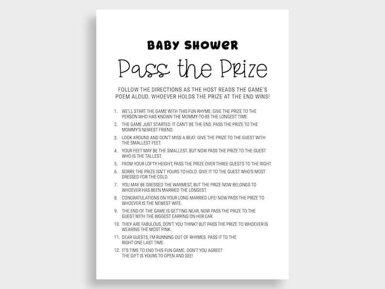 May include: A white paper sign with black text that reads "Baby Shower Pass the Prize." The sign includes instructions for a baby shower game. The text is in a playful, handwritten style.