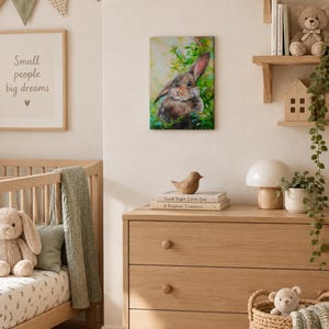 May include: A rectangular wall art print featuring a painting of a brown rabbit nestled among vibrant green foliage. The artwork displays soft brushstrokes and natural tones, depicting the rabbit with alert ears and a gentle expression in a garden.