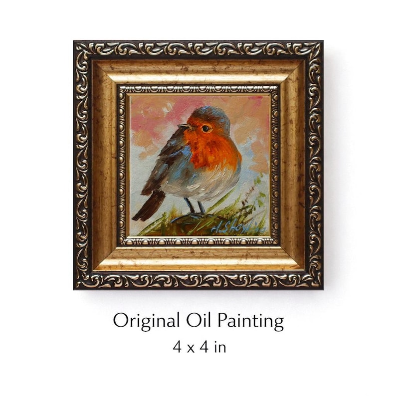 May include: An original oil painting of a robin bird with a red breast and grey wings, set in a decorative gold-toned frame with ornate detailing. The artwork measures 4 x 4 inches and features a soft, painterly background with green foliage.