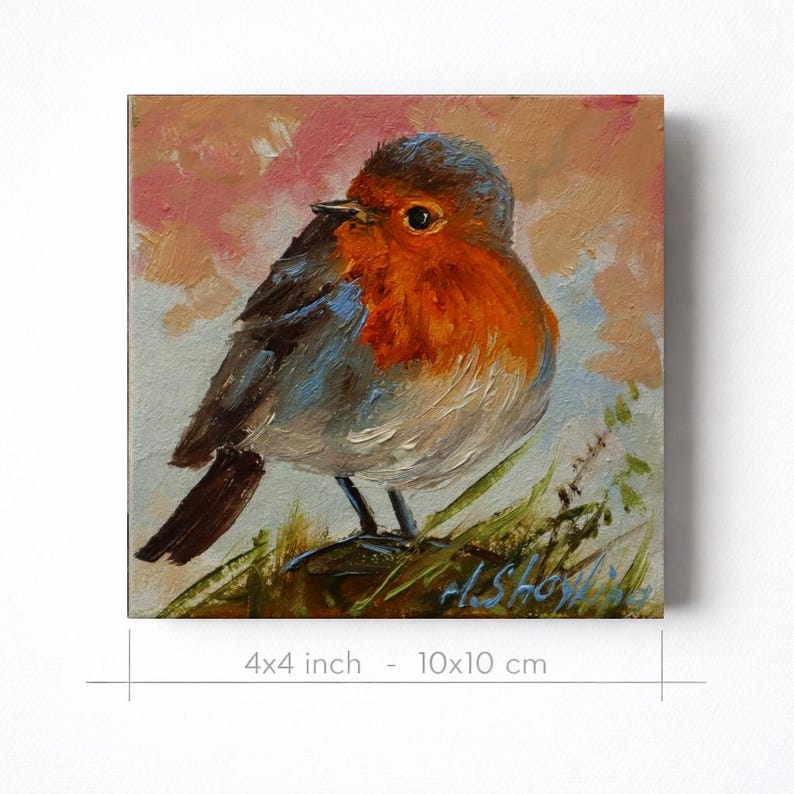 May include: An oil painting on a square canvas measuring 4x4 inches, depicting a robin with a bright orange breast, grey-brown wings, and a dark tail, perched on green grass against a soft, muted pink and blue background with a signature.