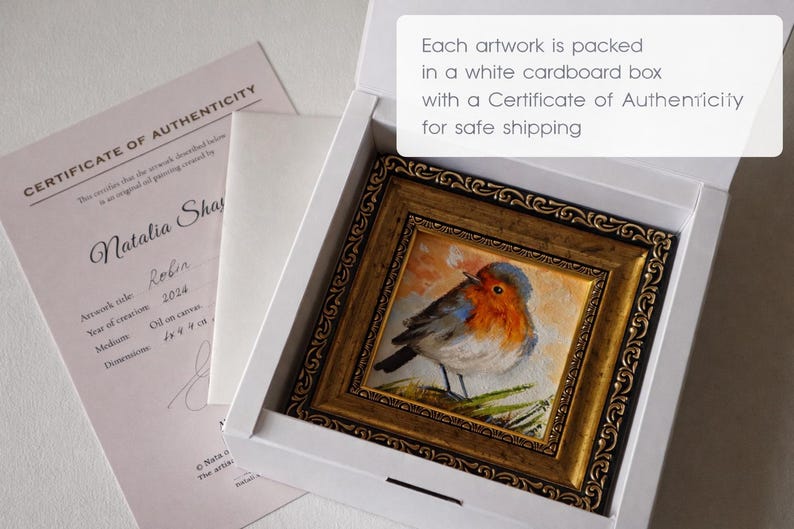 May include: A small oil painting of a robin in an ornate gold frame, nestled inside a white cardboard box. Beside the box lies a Certificate of Authenticity document. The text on the box reads: Each artwork is packed in a white cardboard box with a Certificate of Authenticity for safe shipping.