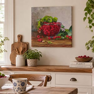 May include: A square canvas wall art print featuring a clear glass bowl filled with bright red raspberries and green leaves, resting on a dark wooden surface against a neutral gray background, capturing a realistic still life fruit arrangement.