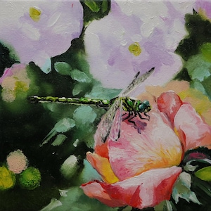 May include: An oil painting of a pink rose with a green and black dragonfly perched on a petal. The background features soft, blurred white and lavender flowers and green foliage. The artwork has a painterly style with visible brushstrokes.