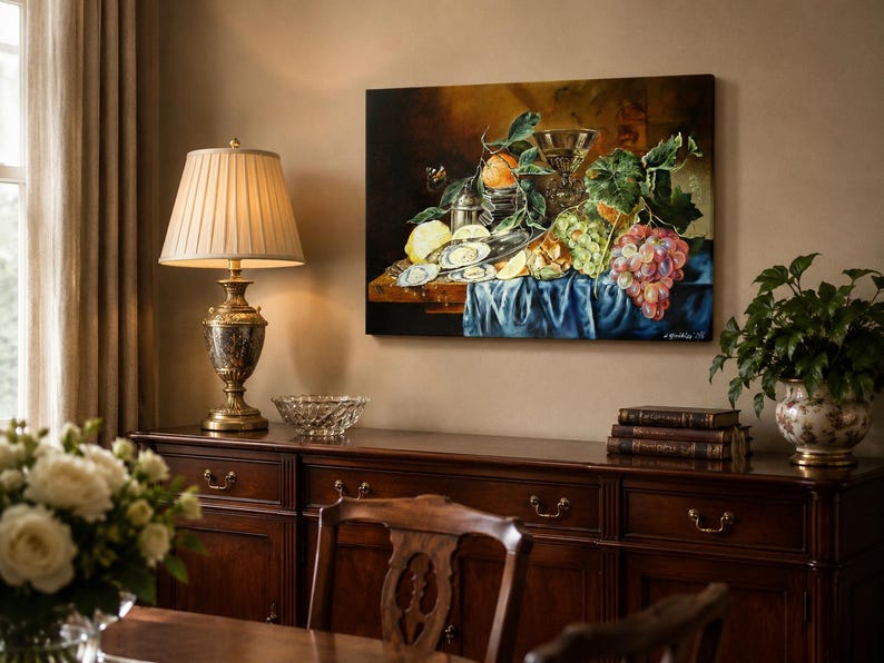 May include: A rectangular oil painting depicting a still life arrangement of oysters, a lemon, green and red grapes, and a glass goblet on a wooden table draped with a blue cloth. The artwork features warm lighting and rich, dark, earthy tones.