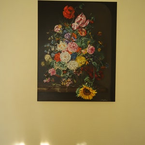 May include: A framed floral still life painting featuring a vibrant bouquet of flowers. The arrangement includes red poppies, white roses, and a large yellow sunflower. The artwork is set against a dark background.