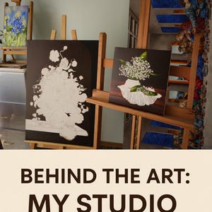 May include: Three wooden easels holding canvases in a studio. One canvas shows a blue iris painting, another features a black and white floral outline, and the third displays a realistic painting of white lily of the valley flowers in a vase.