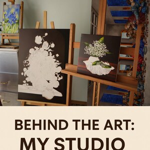 May include: Two paintings on wooden easels. One features a white floral design on a black background. The other depicts white flowers in a white lace-trimmed bowl. The text "BEHIND THE ART: MY STUDIO" is at the bottom of the image.