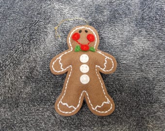 May include: A gingerbread man Christmas ornament made of felt with white buttons and red and green embroidery.