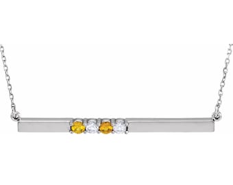 May include: A silver bar necklace with a row of small yellow and white gemstones.