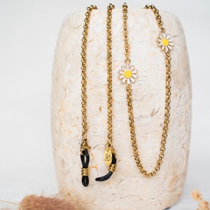 May include: Two gold chain glasses retainers with black rubber ends and small white and yellow daisy charms.