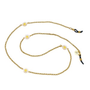 May include: Gold chain with four white and yellow daisy charms. The chain has black rubber ends for attaching to glasses.