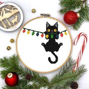 クリスマスホリデー、クリスマスライトからぶら下がる黒猫、ユーモアのあるクロスステッチパターン - PDF デジタルダウンロード
