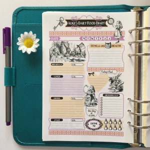 May include: A pink and white Alice in Wonderland themed daily food diary planner with a black and white illustration of Alice and the Mad Hatter. The planner has sections for breakfast, lunch, dinner, snack, fitness, and health. It also includes a shopping list and a section for noting how you feel.