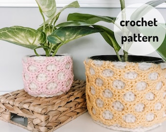 Puede incluir: Dos cubiertas de maceta de ganchillo, una rosa y otra amarilla, sobre un fondo blanco. El texto "crochet pattern" está escrito en un círculo blanco en la imagen.