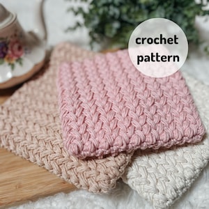 Puede incluir: Tres posavasos de ganchillo en rosa, beige y blanco. Los posavasos están hechos con un patrón de punto simple y tienen un aspecto texturizado. El texto "crochet pattern" está escrito en negro sobre un círculo blanco.