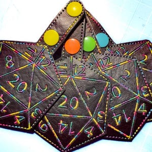 Pode incluir: Um conjunto de bolsas hexagonais castanho-escuras com contornos bordados em cores de arco-íris representando dados de vinte faces com números. Cada bolsa inclui um botão de pressão colorido em amarelo, laranja, verde ou azul.