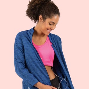 May include: A woman wearing a blue zip-up jacket over a pink sports bra and black leggings. The jacket has a textured, heather-like pattern.