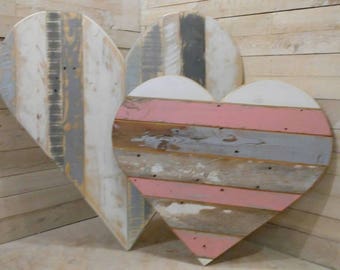 Puede incluir: Tres corazones de madera con un aspecto desgastado y rústico. Los corazones están pintados en tonos de blanco, gris y rosa. Los corazones están dispuestos en fila, con el corazón más grande en el centro.