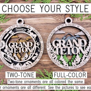 Puede incluir: Dos adornos navide&ntilde;os de madera con un dise&ntilde;o del Parque Nacional Grand Teton. Un adorno es de dos tonos con colores marr&oacute;n y madera natural. El otro adorno es a todo color con colores verde, azul y marr&oacute;n. El texto "Elige tu estilo" est&aacute; en la parte superior de la imagen. El texto "Dos tonos" est&aacute; debajo del adorno de dos tonos. El texto "Color completo" est&aacute; debajo del adorno a todo color. El texto "Los adornos de dos tonos son todos del mismo color. Los adornos a todo color son todos diferentes. Mira las fotos para ver cada parque." est&aacute; en la parte inferior de la imagen.