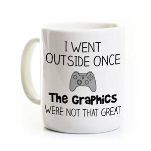 May include: White ceramic coffee mug with a black graphic of a video game controller and the text "I went outside once. The graphics were not that great."