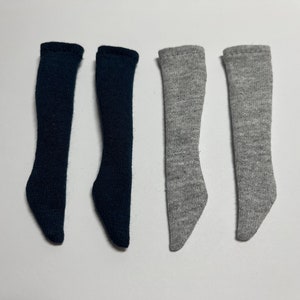 Könnte beinhalten: Vier Paar Kniestrümpfe, zwei Paar sind schwarz und zwei Paar sind grau.