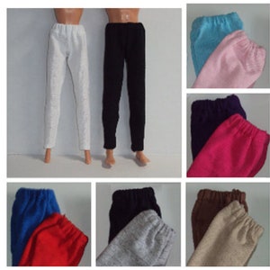 May include: A set of ten pairs of doll pants in various colors, including white, black, blue, pink, purple, red, brown, and gray. The pants are made of a soft, stretchy fabric and have an elastic waistband.
