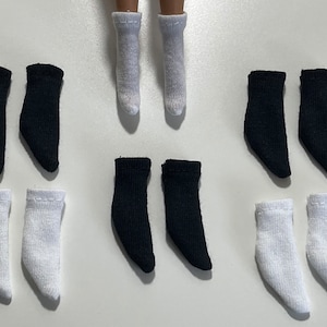 Könnte beinhalten: Ein Set mit zehn Puppensocken in Schwarz und Weiß. Die Socken sind knöchellang und haben eine gerippte Struktur.