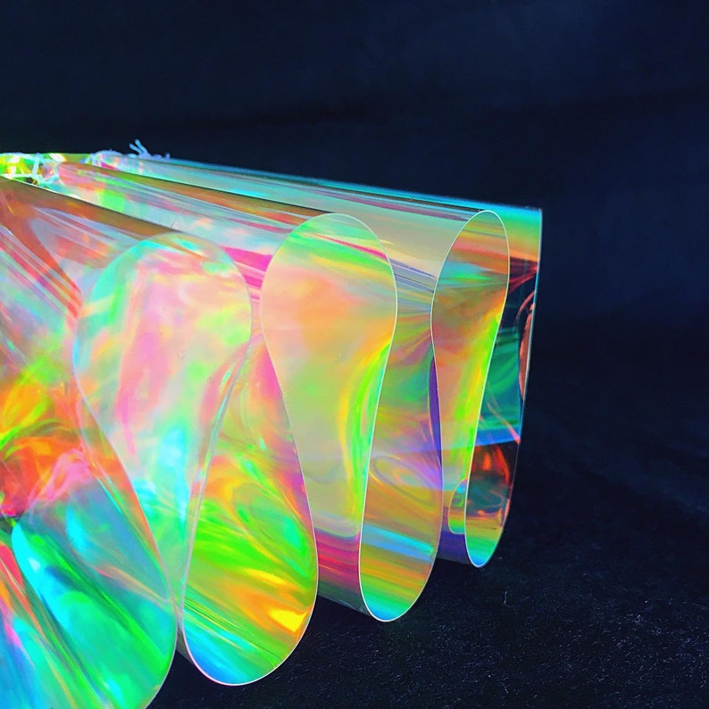May include: A stack of iridescent holographic vinyl sheets with a rainbow of colors, including pink, green, blue, and yellow.