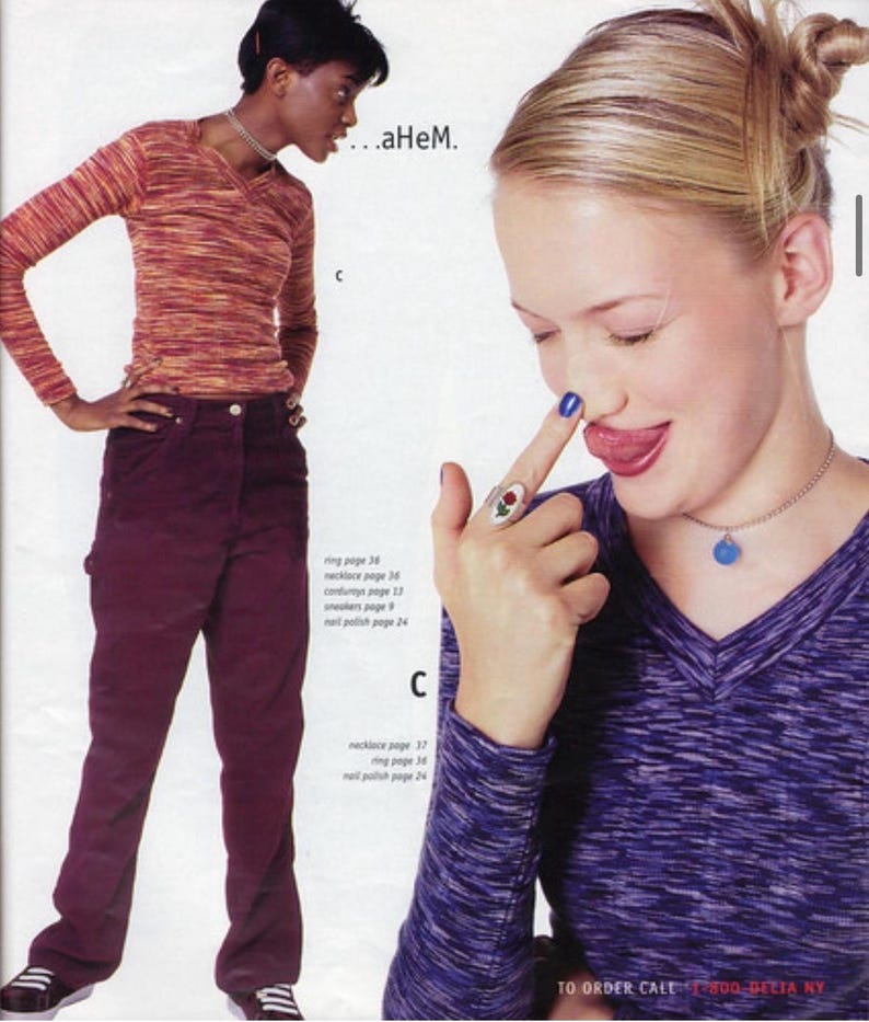 May include: A fashion magazine spread featuring two models. One model wears a long-sleeved, orange and brown striped shirt and burgundy pants. The other model wears a purple and gray long-sleeved shirt and a silver necklace with a blue pendant.