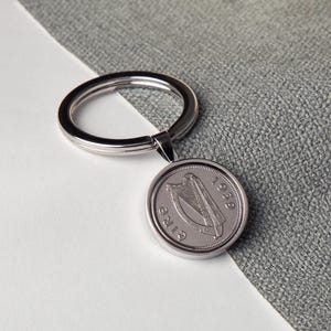 May include: Silver keychain featuring a silver coin with the Irish harp and the year 1979.