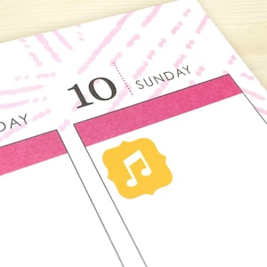 Puede incluir: Primer plano de un planificador semanal con la fecha "10" y la palabra "SUNDAY" escrita encima. Una pegatina amarilla con un icono de nota musical est&aacute; colocada en la secci&oacute;n del domingo.