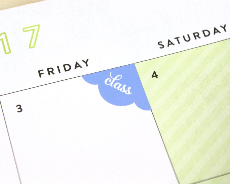 May include: A close-up of a calendar page with the word "Friday" and the number "3" written on it. A blue sticker with the word "class" is placed on the corner of the page, covering part of the number "4" on the next page.
