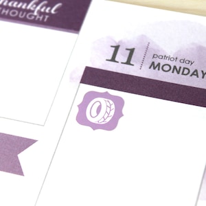 May include: A close-up of a planner page with a purple and white color scheme. The page features the date "11 patriot day MONDAY" and a decorative icon. The words "thankful thought" are visible at the top of the page.