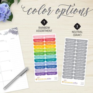 May include: Two sets of planner stickers labeled "homework" in rainbow and gray color options. The rainbow assortment includes stickers in various colors, while the neutral option features gray stickers. The stickers are displayed on a wooden surface with a calendar and pen.