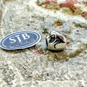 Pu&ograve; includere: Ciondolo in argento con un design a forma di cuore e un adesivo ovale nero con la scritta "SJB - Jewellery Bliss".