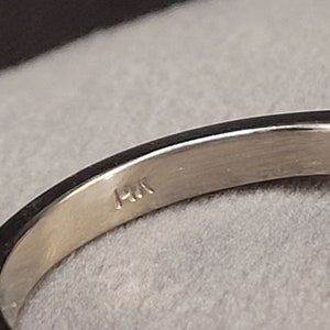 May include: Close-up of the inside of a silver ring with the inscription "14K" on the band.