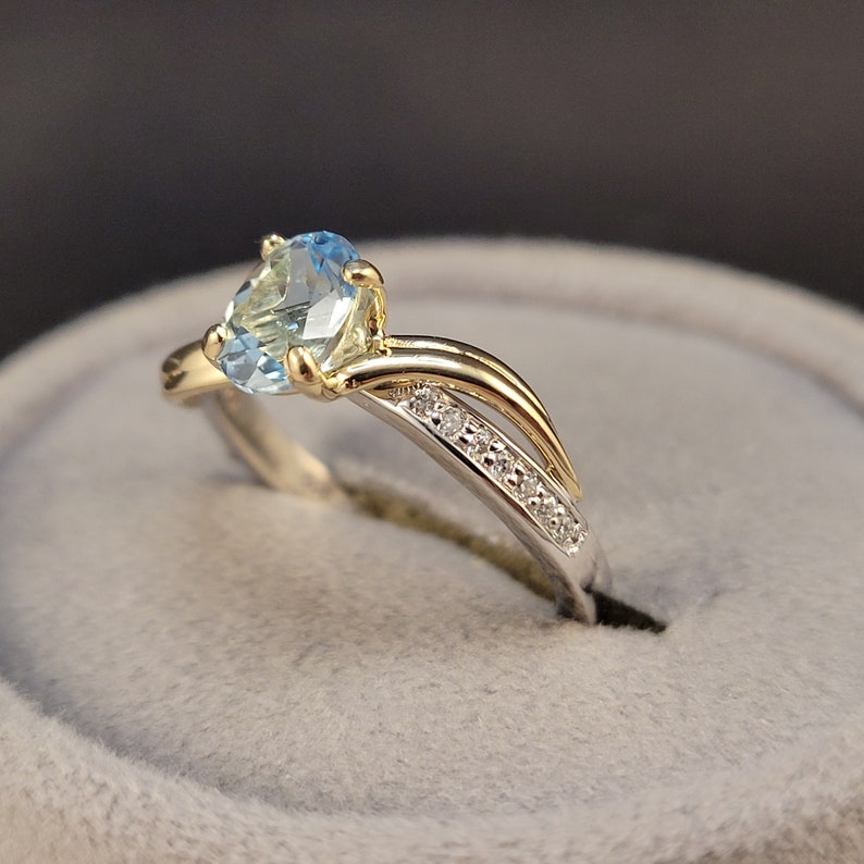 May include: A gold ring with a light blue oval gemstone and a row of small diamonds on the band.
