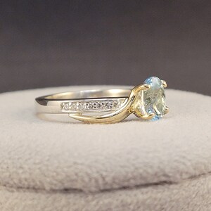 May include: A gold and silver ring with a blue gemstone and a row of small diamonds.