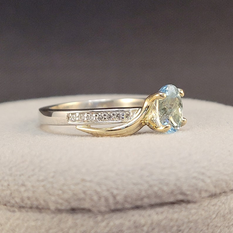 May include: A gold and silver ring with a blue gemstone and a row of small diamonds.